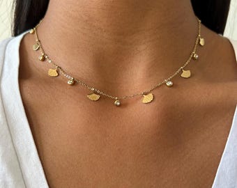 May include: A gold necklace with small, delicate fan-shaped charms and clear crystal accents.