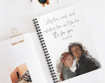 May include: A spiral bound notebook with a quote about love. The quote reads "My true, real, and abiding love isn't for her. It's for you." - Ross Poldark. The notebook features a watercolor painting of a couple embracing.