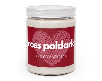 May include: A white candle jar with a red label. The label has a pink heart with a scribbled design and the text "ross poldark is my valentine".