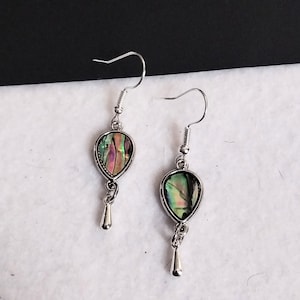 May include: A pair of silver dangle earrings with iridescent abalone shell teardrop-shaped charms. The charms have a silver border and are suspended from a silver chain.