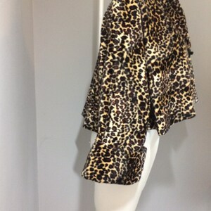 May include: A cropped leopard print jacket with long sleeves and a button closure. The jacket is made of a soft, plush fabric.