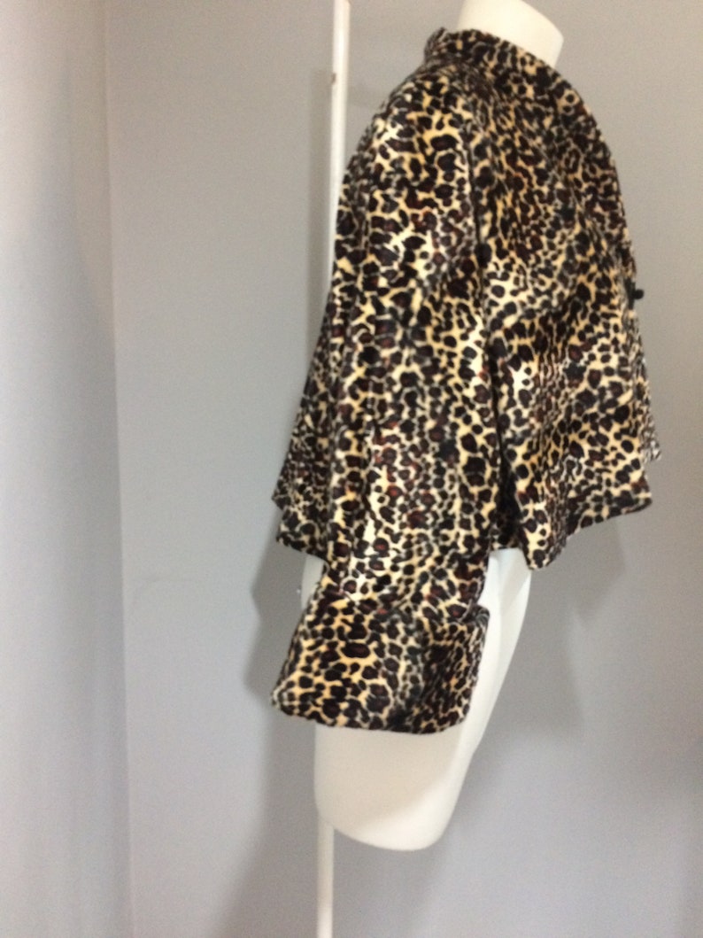 May include: A cropped leopard print jacket with long sleeves and a button closure. The jacket is made of a soft, plush fabric.