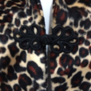 May include: Close-up of a black and brown leopard print fabric with a black fabric knot closure.