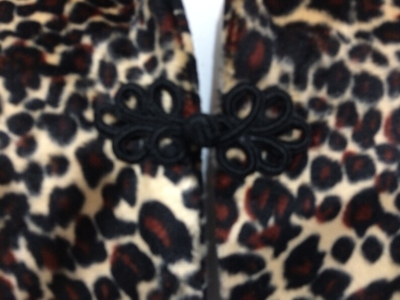 May include: Close-up of a black and brown leopard print fabric with a black fabric knot closure.