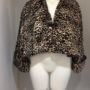 May include: A cropped leopard print jacket with long sleeves and a button closure. The jacket is made of a soft, plush fabric.
