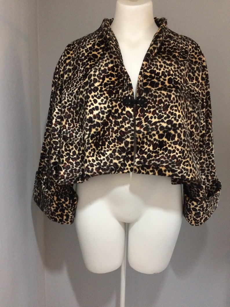 May include: A cropped leopard print jacket with long sleeves and a button closure. The jacket is made of a soft, plush fabric.