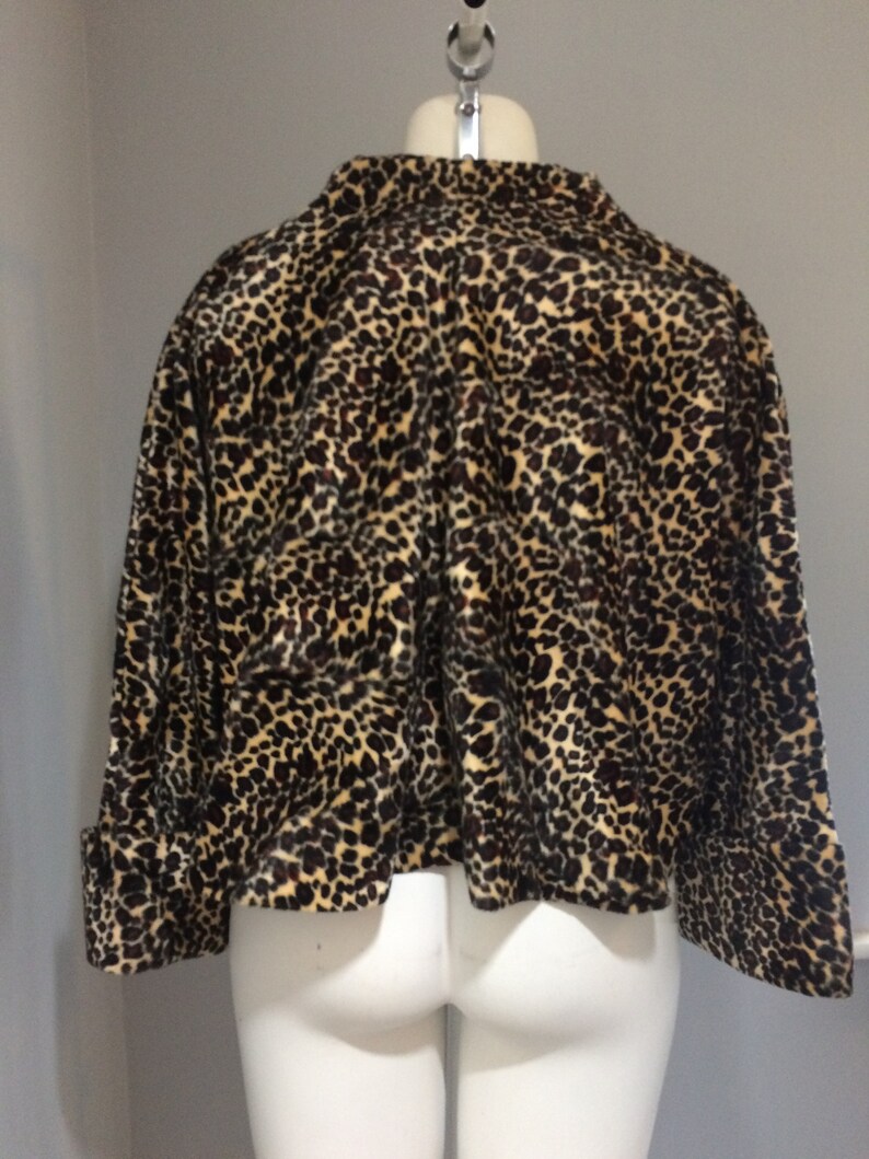 May include: A brown and tan leopard print cropped jacket with long sleeves and a high neckline.