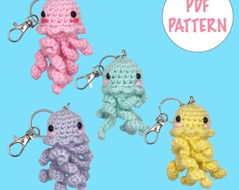 May include: Four crocheted jellyfish keyrings in pink, light blue, purple, and yellow. Each keyring has a silver key ring and a cute face with black eyes and pink cheeks.