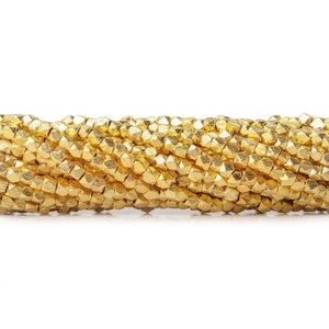 May include: A strand of gold-colored metal beads. The beads are faceted and have a slightly irregular shape.