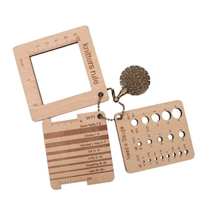 May include: A wooden knitting gauge tool with multiple sections. It includes a square ruler with "knitters rule" text, a needle gauge with various hole sizes, and a section for yarn weight. The tool has a decorative metal charm.
