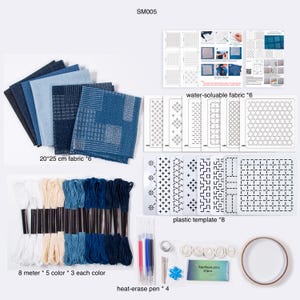 May include: A sashiko embroidery kit labeled SM005 containing six 20x25 cm fabric pieces in blue shades, six water-soluble fabric sheets, eight plastic templates, fifteen 8-meter embroidery threads, four heat-erase pens, needles, thimbles, and pins.