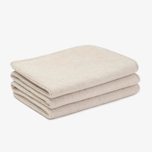 May include: A stack of three cream-colored waffle weave towels folded neatly.