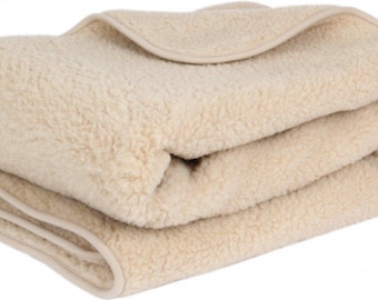 May include: A cream-coloured sheepskin throw blanket folded in half. The blanket has a soft, fuzzy texture and a subtle sheen.