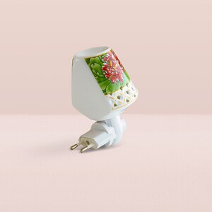 K&ouml;nnte beinhalten: Wei&szlig;es, steckbares Nachtlicht aus Keramik mit Blumenmuster. Das Nachtlicht hat ein wei&szlig;es Kabel und einen Stecker mit zwei Stiften.