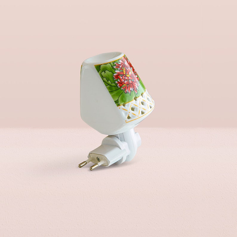K&ouml;nnte beinhalten: Wei&szlig;es, steckbares Nachtlicht aus Keramik mit Blumenmuster. Das Nachtlicht hat ein wei&szlig;es Kabel und einen Stecker mit zwei Stiften.