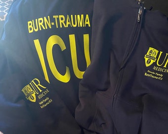May include: Two black hoodies with yellow text and logos. One hoodie says "BURN-TRAUMA ICU" and the other says "UR MEDICINE Kessler Family Burn/Trauma ICU".