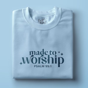 Puede incluir: Camiseta azul claro con el texto "made to worship" y "PSALM 95:1" impreso en la parte delantera.