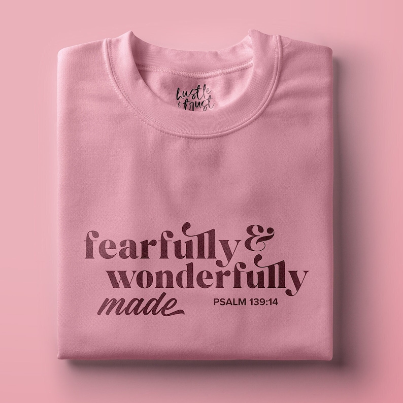 Pu&ograve; includere: Maglietta rosa con la scritta "fearfully & wonderfully made" e "PSALM 139:14" stampata sul davanti.