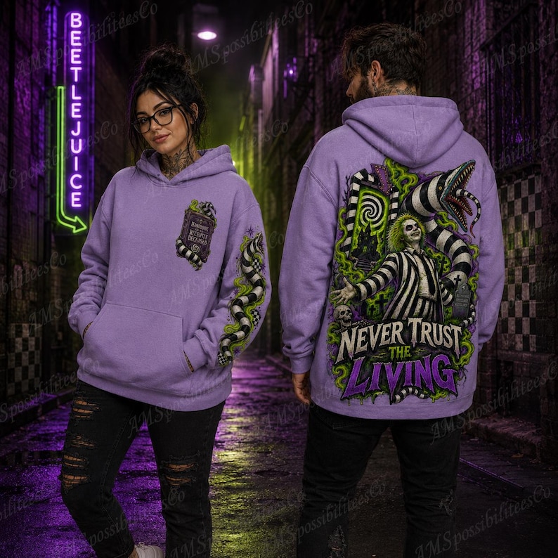 Puede incluir: Una sudadera con capucha de color morado claro que presenta un gr&aacute;fico de un personaje con traje a rayas, una serpiente y el texto "NEVER TRUST THE LIVING" en la espalda, con un gr&aacute;fico m&aacute;s peque&ntilde;o del "Handbook for the Recently Deceased" en el pecho.