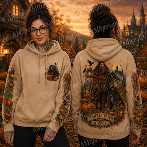 Puede incluir: Una sudadera con capucha de color beige que presenta un gráfico de una figura barbuda sosteniendo una linterna con un perro grande en un huerto de calabazas en la espalda. El frente muestra una versión más pequeña del perro y la calabaza. Las mangas tienen patrones de enredaderas.