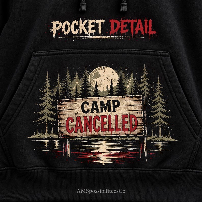 May include: A black hoodie featuring a graphic print of a wooden sign that reads CAMP CANCELLED in red letters. The design includes a forest of pine trees, a full moon, and a reflection in water. The text POCKET DETAIL is printed above the pocket.