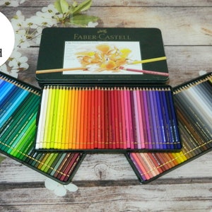 May include: A set of 120 Faber-Castell Polychromos colored pencils in a tin box. The pencils are arranged in rows by color, with the colors ranging from blues and greens to yellows, oranges, reds, pinks, purples, and grays. The tin box has a green background with the Faber-Castell logo and the words "Polychromos Colored Pencils" printed on it.