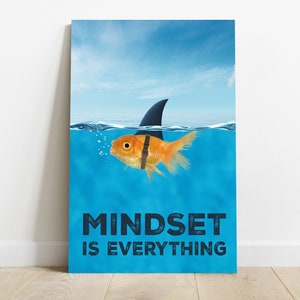 Può includere: Un poster motivazionale con un pesce rosso che indossa una pinna di squalo che nuota in acqua blu. Il testo sul poster recita "Mindset is Everything".
