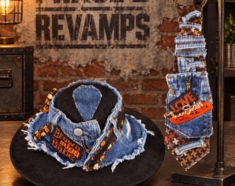 May include: A black hat with a distressed blue denim band featuring frayed edges, a metal button, and an orange patch with black text. Beside it, a necktie made of patchwork denim and brown patterned fabric with a pocket and an orange patch.