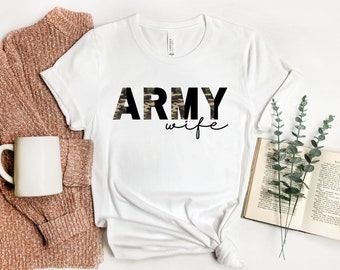 Könnte beinhalten: Weißes T-Shirt mit den Worten "ARMY wife" in schwarzer Schrift. Das Wort "ARMY" ist in Tarnmuster.