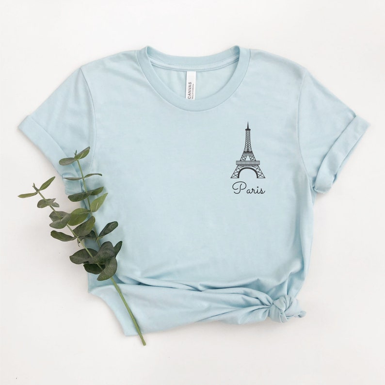May include: A light blue t-shirt with a black outline of the Eiffel Tower and the word "Paris" printed on the front.