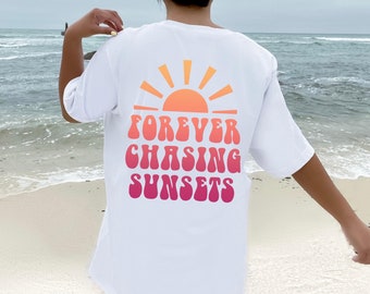 May include: White t-shirt with a graphic of a sunset and the text "FOREVER CHASING SUNSETS" in a gradient of pink, orange, and yellow.