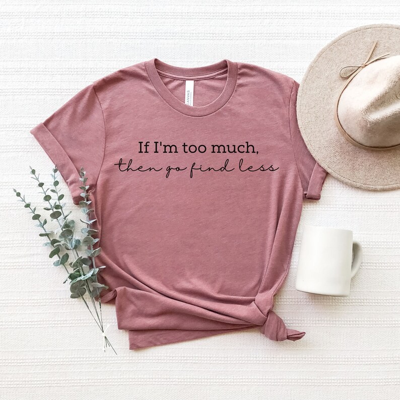 Op de afbeelding: Een mauve t-shirt met de tekst "If I'm too much, then go find less" in het zwart.