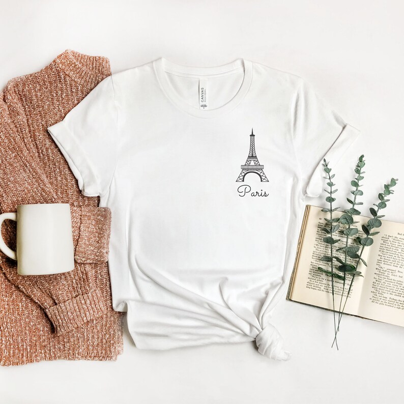 May include: White t-shirt with a black outline of the Eiffel Tower and the word "Paris" underneath.