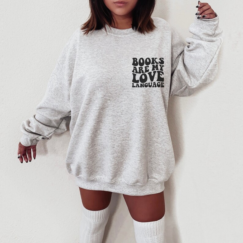May include: A gray sweatshirt with the text "BOOKS ARE MY LOVE LANGUAGE" in black retro-style lettering.
