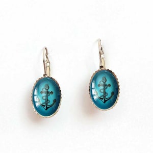 May include: A pair of silver dangle earrings with a blue oval-shaped charm featuring a black anchor with rope detail.