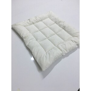 May include: A white quilted square cushion with a soft, plush texture. The cushion is made of a lightweight fabric and has a simple, modern design.
