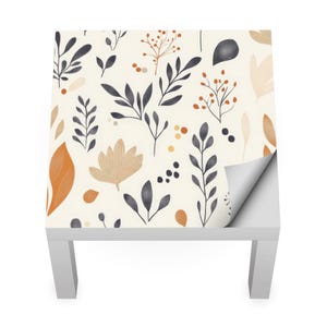 May include: A white table with a peel-and-stick wallpaper featuring a repeating pattern of stylized leaves and berries in shades of orange, brown, and blue.