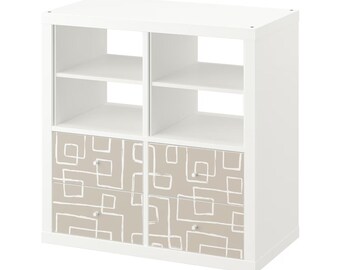 May include: White cube storage shelf with two drawers. The drawers have a beige background with a white geometric pattern.
