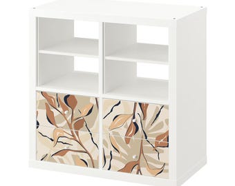 May include: White cube storage shelf with two drawers. The drawers have a beige and brown abstract leaf pattern.