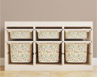 May include: A white wooden shelf unit with six storage bins. The bins are decorated with a floral pattern in shades of pink, yellow, and green.