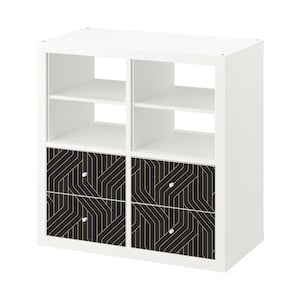 Pode incluir: Unidade de prateleira de cubo branco com quatro gavetas. As gavetas têm um padrão geométrico preto e dourado.