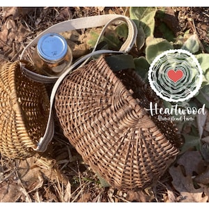 May include: Two woven brown baskets with a cream-colored strap, one holding a glass jar with a silver lid. The baskets are on a bed of leaves and foliage. The logo for Heartwood Homestead Farm is visible.