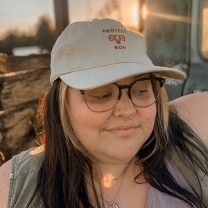 Pro Roe Reproductive Rights Ball Cap in nude, cream color. This hat represents Abortion rights, as well as women's rights. Pro choice hat depicts embroidered uterus, reading "Pro Roe."