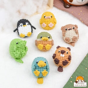 May include: A collection of crocheted animal amigurumi toys. The toys include a penguin, a duck, a beaver, a frog, a duckling, and a chick. The toys are all made with different coloured yarn and have different facial expressions.