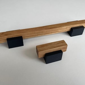 Può includere: Maniglie per mobili in legno con finitura a venatura naturale e basi nere. Il set include una maniglia lunga e una più piccola, ideali per cassetti o armadi. L'hardware è in legno e verniciato di nero.