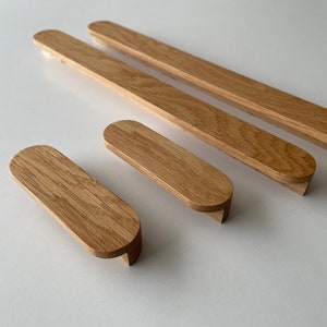 Puede incluir: Cuatro tiradores de armario de madera en varios tamaños. Los tiradores son de forma ovalada con un acabado de madera natural liso.