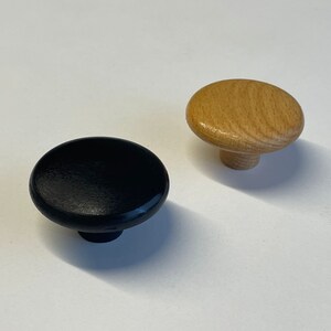 Puede incluir: Dos pomos redondos de madera, uno negro y otro de madera natural.