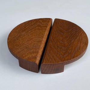 May include: Two wooden half-circle cabinet pulls with a natural wood finish. The pulls are made of solid wood and have a smooth, rounded surface.