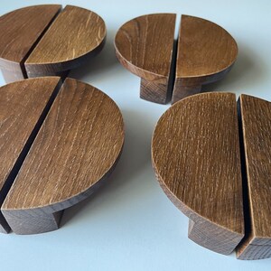 Può includere: Quattro maniglie per ante di armadio in legno marrone con un design diviso. Ogni maniglia è un semicerchio con una superficie piatta e un bordo arrotondato.