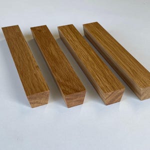 Può includere: Quattro tiretti per cassetti in legno con finitura in legno naturale. I tiretti sono di forma rettangolare con un'estremità leggermente affusolata.